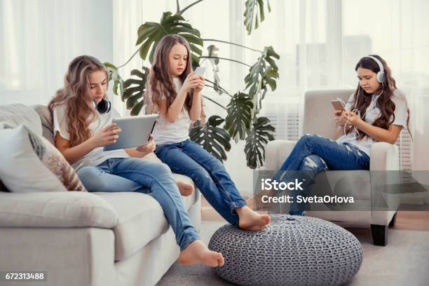 Kids With Phones And Tablets With Smartphones And Headphones Group Of Teenage Girls Is Using Gadgets Stock Photo - Download Image Now