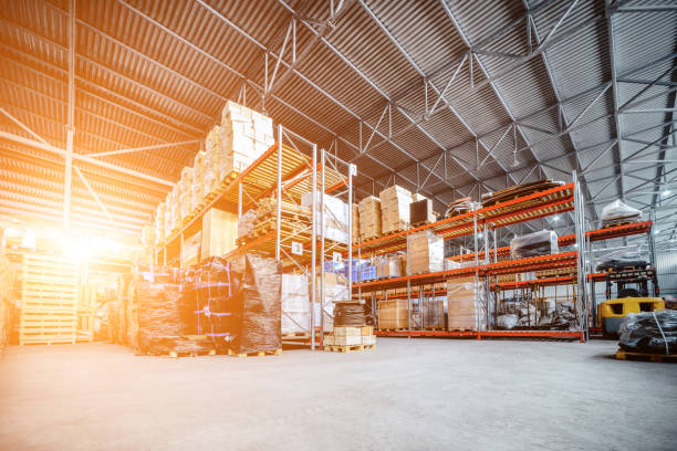Large hangar warehouse industrial and logistics companies Large hangar warehouse industrial and logistics companies. Warehousing on the floor and called the high shelves. Toning the image. construction material stock pictures, royalty-free photos & images