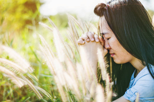 istock Woman praying in meadow at sunset 672320888