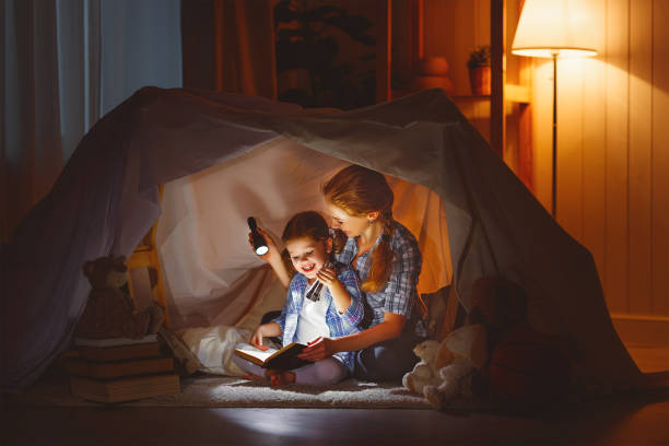 istock mother and child daughter with a book and a flashlight before going to bed 672340528