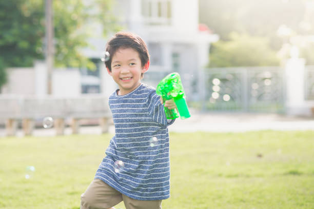 istock Asian child Shooting Bubbles from Bubble Gun 672343576