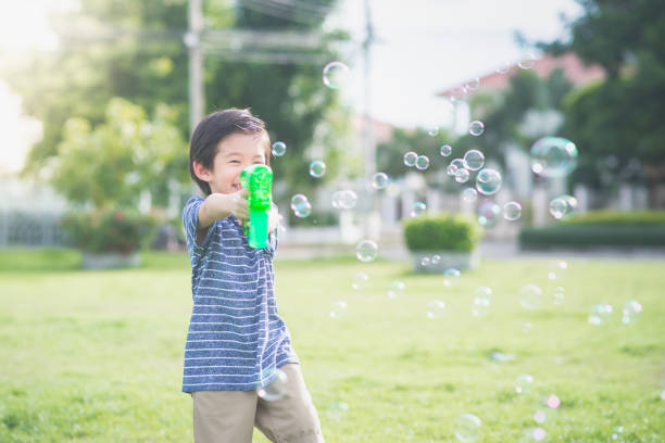 istock Asian child Shooting Bubbles from Bubble Gun 672343632