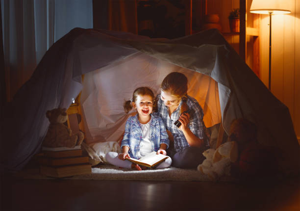 istock mother and child daughter with a book and a flashlight before going to bed 672343678