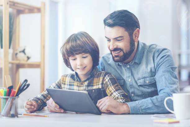 istock Father and son playing with digital tablet at desk 672347220