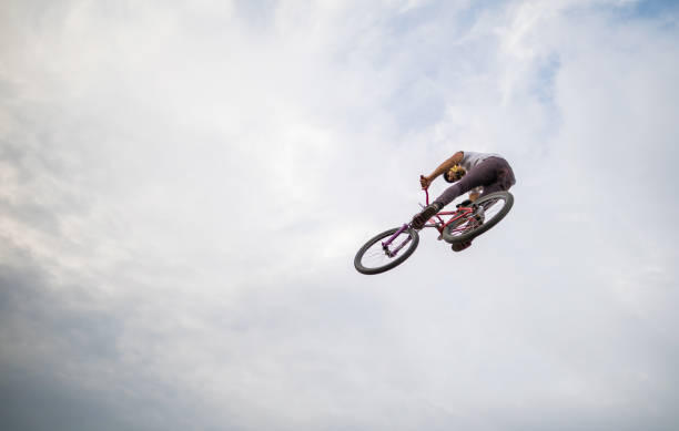 istock Directly below view of man on mountain bicycle against sky. 672347362