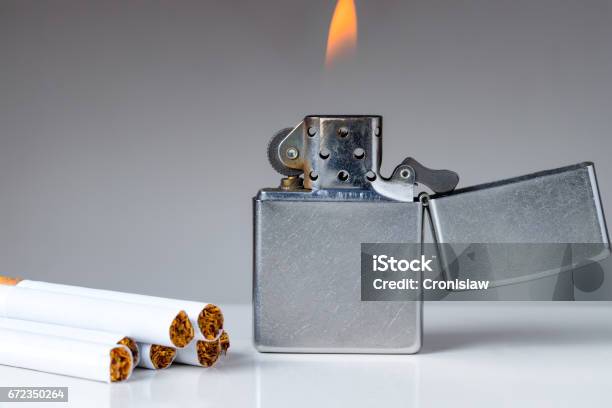 Cigarettes And Lighter With Flame On White And Grey Background Stock Photo - Download Image Now