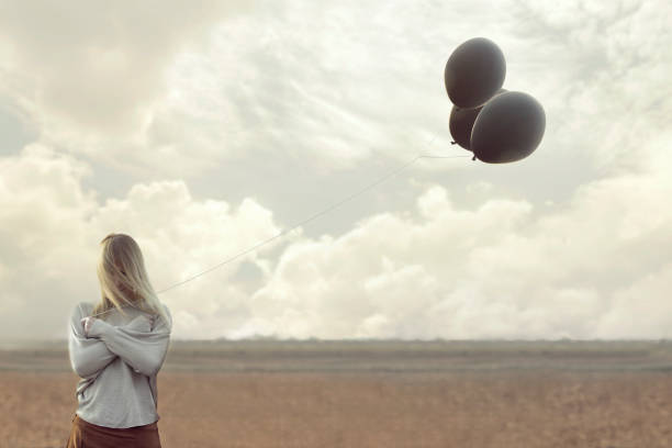 istock solitude woman with blacks balloons hid her face 672351252