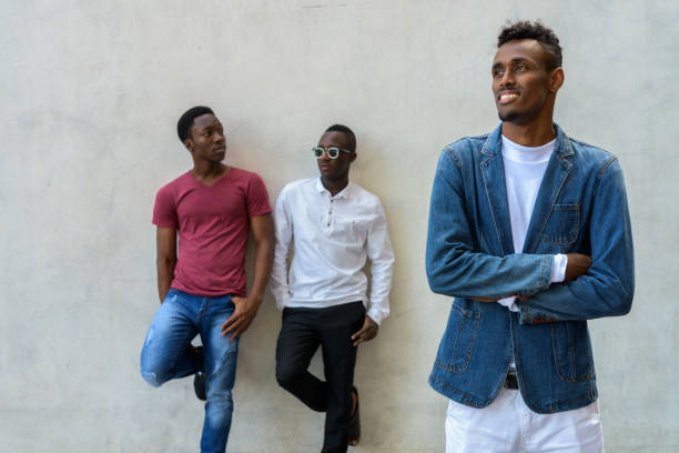 istock Group of three young African men against gray concrete wall 672369486