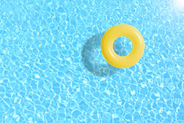 istock yellow swimming pool ring float in blue water. concept color summer. 672372530