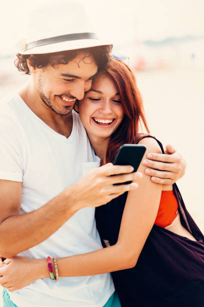 istock Young couple texting at the beach 672372830