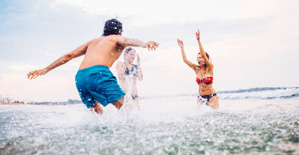 istock Friends splashing each other with water 672372838