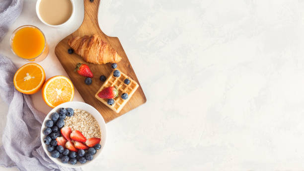 istock Breakfast table with granola, coffee, croissant, viennese waffles, orange and fresh berries. Copy space 672376914