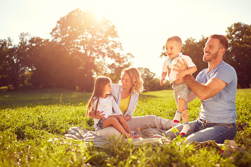 Young parents with children on picnic in nature at summer