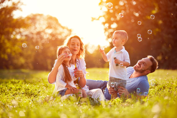family with children blow soap bubbles - enjoyment spring park small imagens e fotografias de stock
