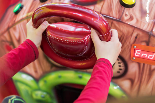 istock Children hands hold steering wheel of simulator 672380554
