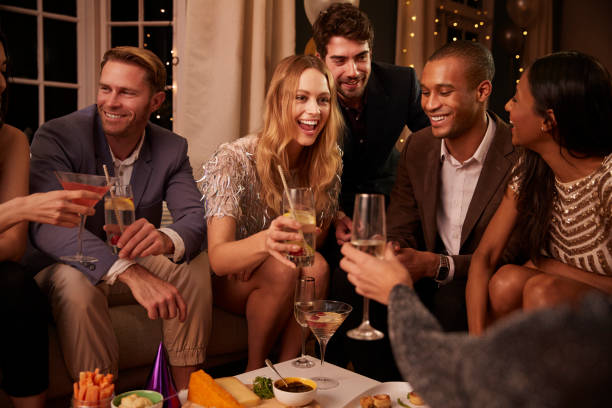 istock Group Of Friends Enjoying Drinks And Snacks At Party 672381482