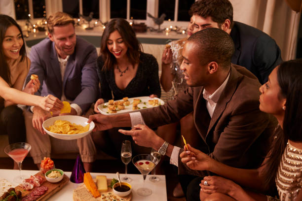 istock Group Of Friends Enjoying Drinks And Snacks At Party 672381484