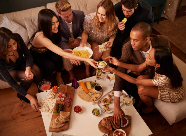 istock Group Of Friends Enjoying Drinks And Snacks At Party 672381506