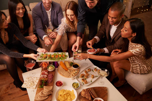 istock Group Of Friends Enjoying Drinks And Snacks At Party 672381546