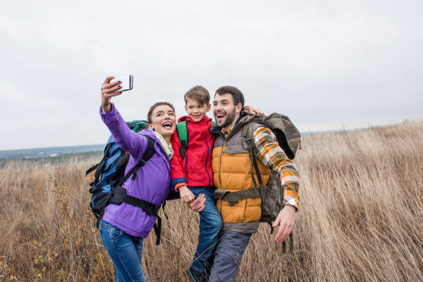 istock Happy family with backpacks taking selfie 672386256