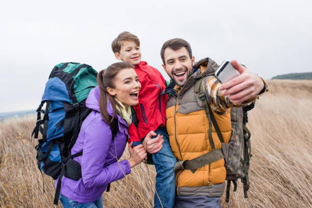 istock Happy family with backpacks taking selfie 672386404