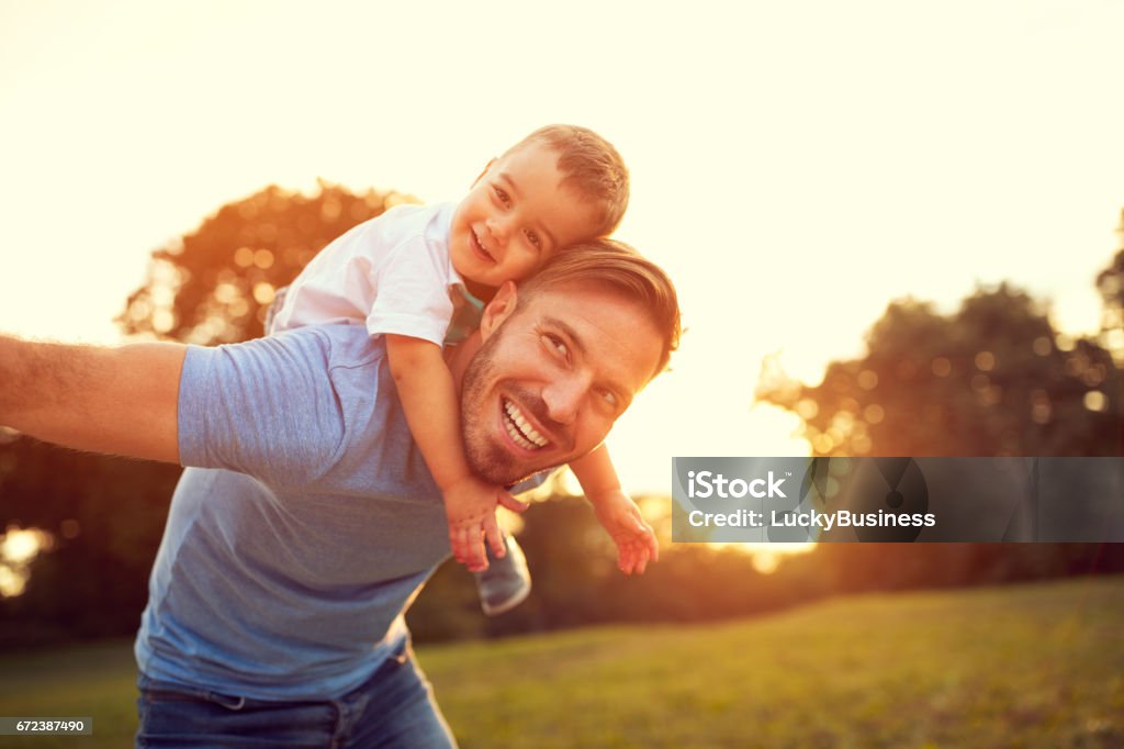 Padre piggyback suo figlio fuori - Foto stock royalty-free di Padre