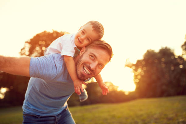 Father piggyback his son outside Father piggyback his little son outside single father stock pictures, royalty-free photos & images