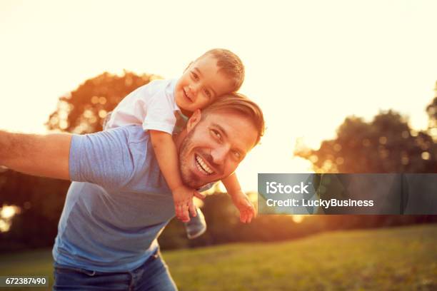 Father Piggyback His Son Outside Stock Photo - Download Image Now - Father, Family, Men