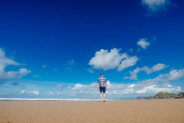 istock Man walking along Watergate Bay beach on a beautiful day. 672389086