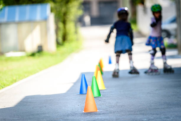 istock Children learning to roller skate on the road with cones. 672390328