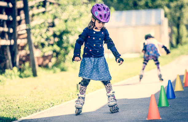 istock Children learning to roller skate on the road with cones. 672391708