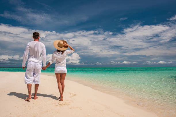 istock Couple in white walking on a beach at Maldives 672397462