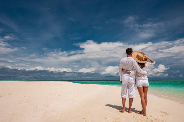 istock Couple in white walking on a beach at Maldives 672397464