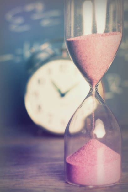 istock Hourglass on wood with a blackboard background 672403172
