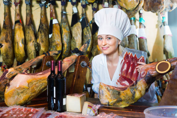 istock Female seller wearing uniform working with iberian ham 672418482