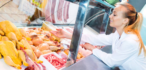 istock Female seller wearing uniform working with fresh meat 672418534
