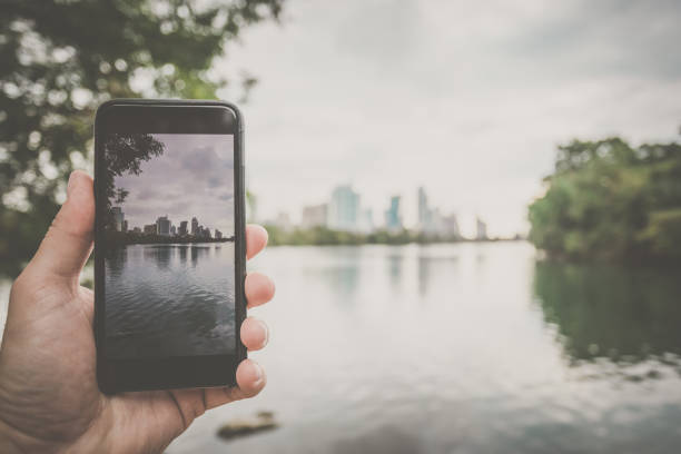 Human Hand Holding a Smart Phone and taking pictures in Austin Texas
