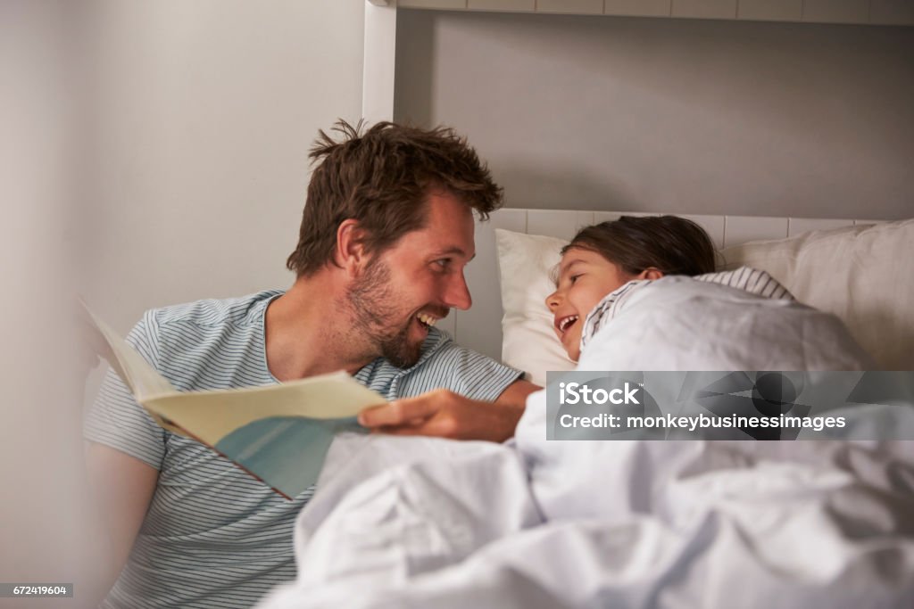 Father Reading Story To Daughter At Bedtime Storytelling Stock Photo