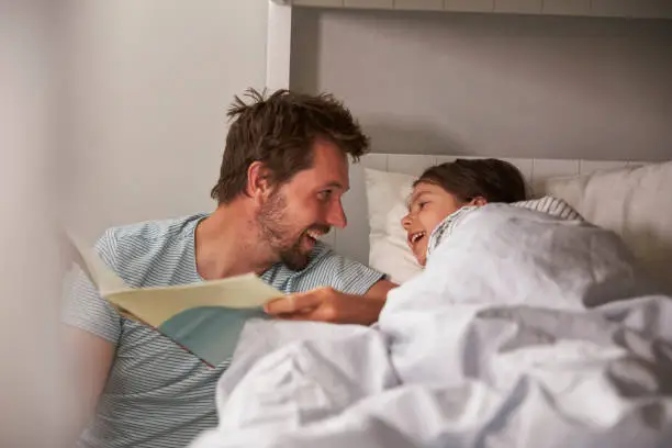 Father Reading Story To Daughter At Bedtime