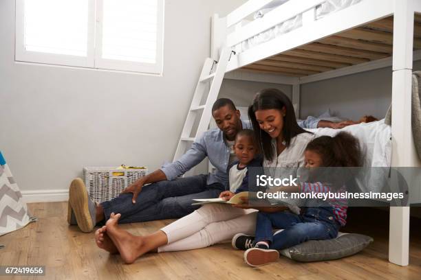 Parents Reading Story To Children In Their Bedroom Stock Photo - Download Image Now - Family, African Ethnicity, Reading