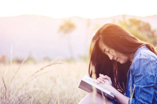 istock Woman praying in meadow at sunset 672421962