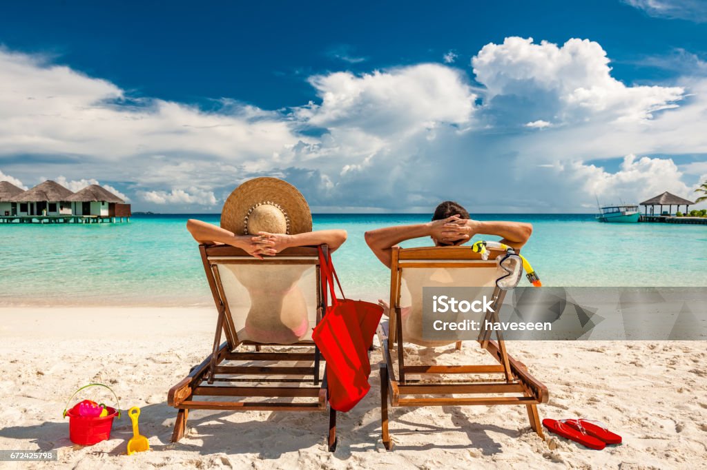 Casal em espreguiçadeiras na praia das Maldivas - Foto de stock de Praia royalty-free