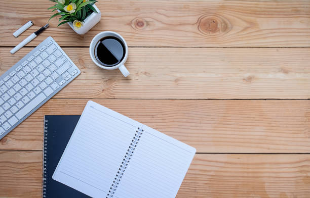 istock Office desk table with keyboard, notebook, pen, cup of coffee and flower. Top view with copy space. (selective focus) 672426766