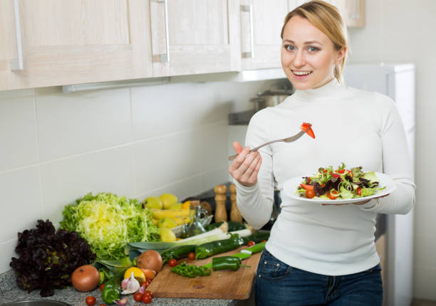 istock Happy girl with vegetable salad in kitchen 672432512
