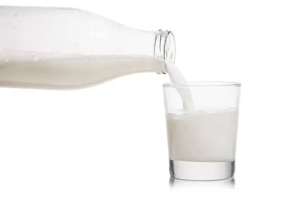 glass bottle pouring milk into a glass on white background