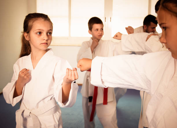 istock Happy children sparring in pairs in karate class 672436808