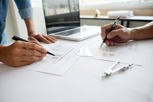 istock Architects engineer discussing at the table with blueprint - Closeup on hands and project print. 672436874