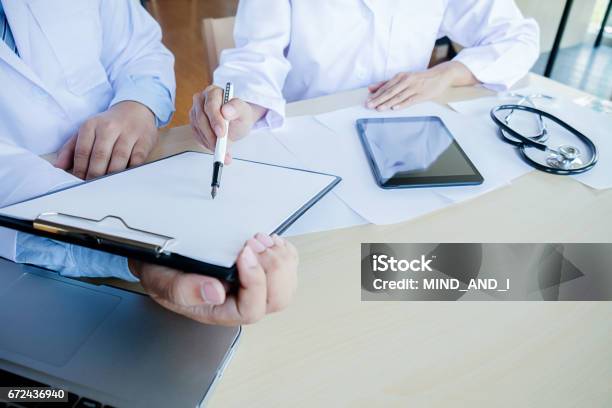 Patient Listening Intently To A Male Doctor Explaining Patient Symptoms Or Asking A Question As They Discuss Paperwork Together In A Consultation Stock Photo - Download Image Now