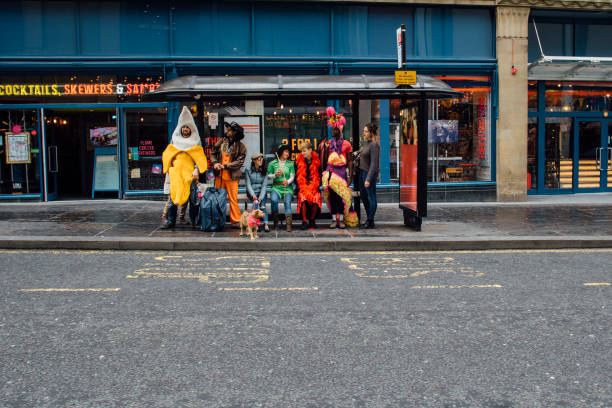 Fundraisers Waiting For The Bus Group of adults are sitting in a bus stop dressed in funny themed costumes. They have a pet dog with them. stage costume stock pictures, royalty-free photos & images