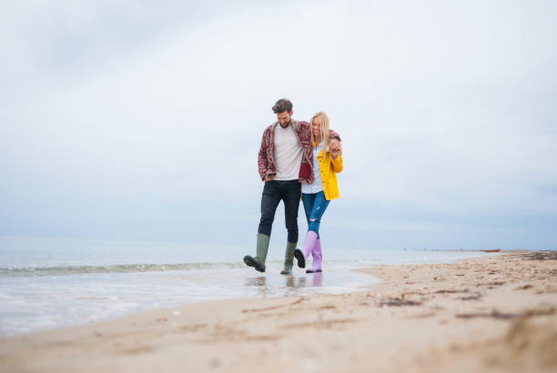 couple marchant sur la plage - beach nature outdoors overcast photos et images de collection
